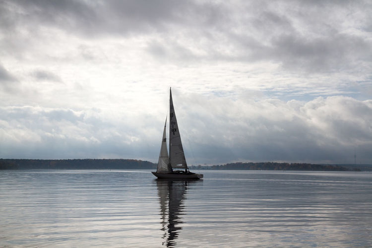 Sailboat sailing in lake against sky