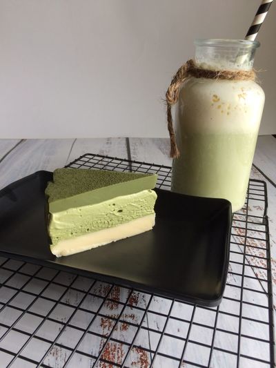 No-bake matcha cheesecake with green tea on black plate for high tea