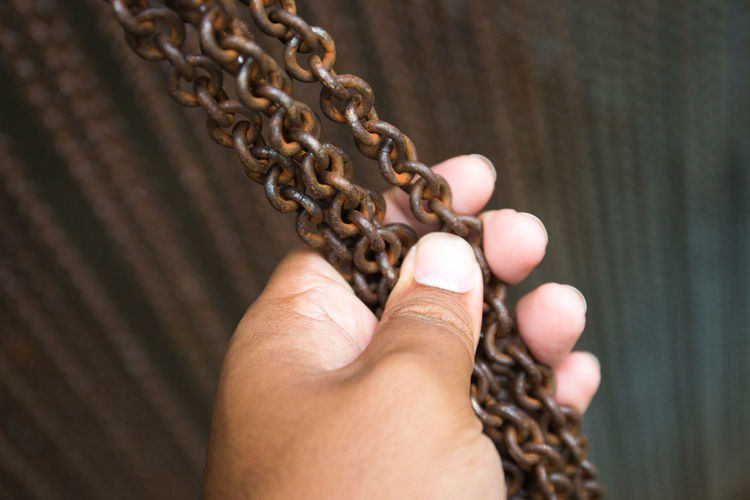 Cropped image of hand holding metallic chain