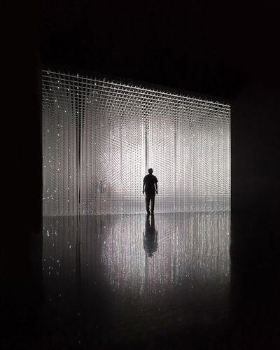 Rear view of silhouette man walking in illuminated building