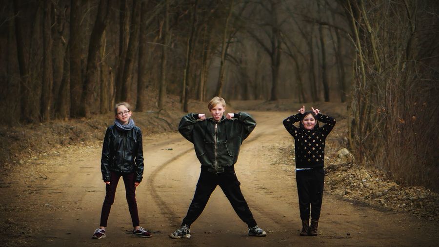 Threea siblings creatively posing for portrait in the forest. 