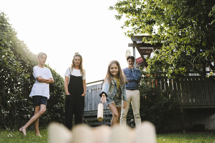 Girl playing molkky with family in back yard