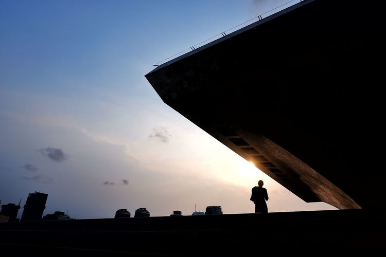 Low angle view of silhouette people standing against sky during sunset