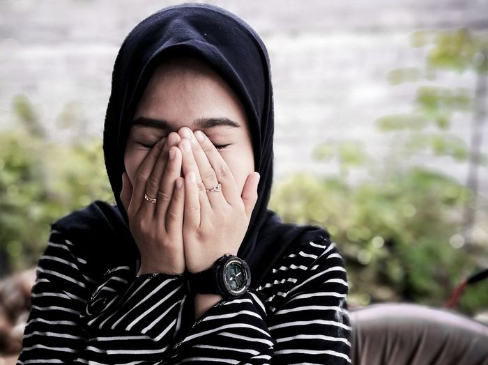 Close-up of young woman wearing hijab covering mouth