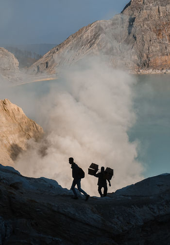 People by crater lake on mountain