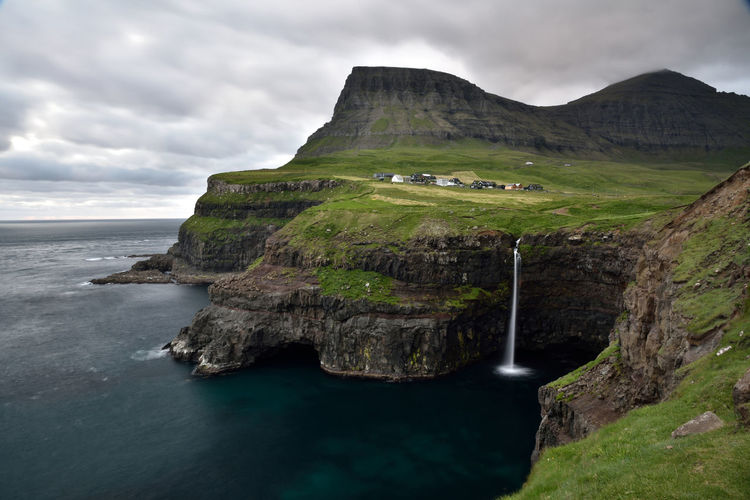 Scenic view of sea, waterfall and gasadalur village at faroe islands