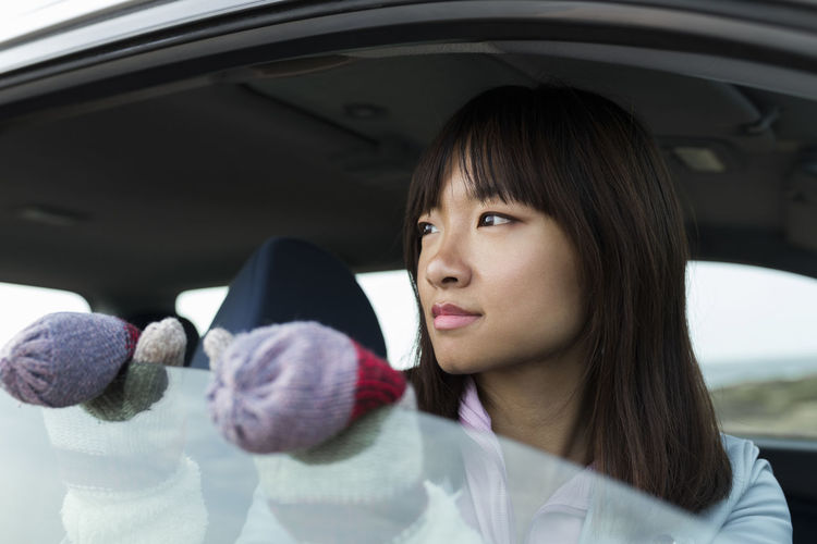 Young chinese woman sitting in a car looking out the car window