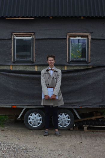 Portrait of young man standing against travel trailer