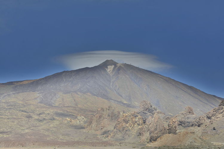 Scenic view of volcanic mountain against blue sky