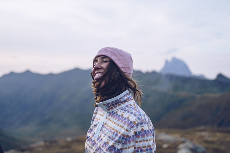 Smiling woman wearing knit hat standing on mountain around ibones of anayet
