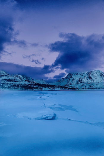 Scenic view of frozen lake and snowcapped mountains against sky