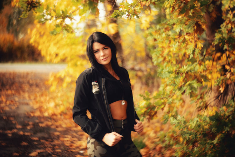 Portrait of smiling young woman standing on land during autumn