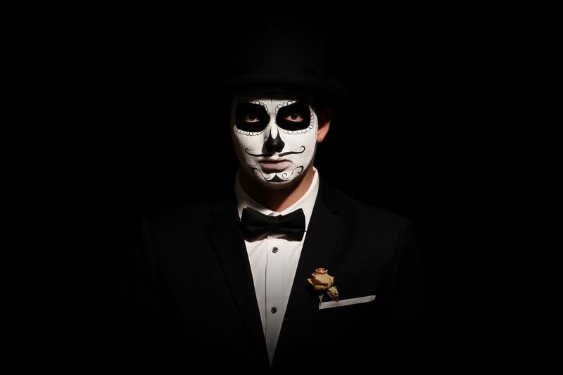 Portrait of man with day of the dead make-up against black background