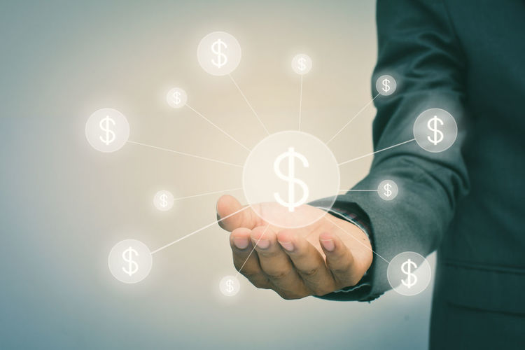 Digital composite of businessman holding dollar symbol