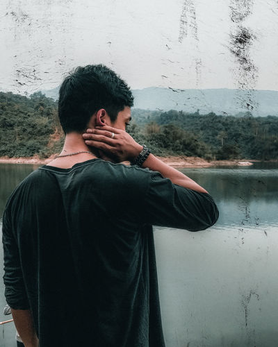 Rear view of man standing by lake