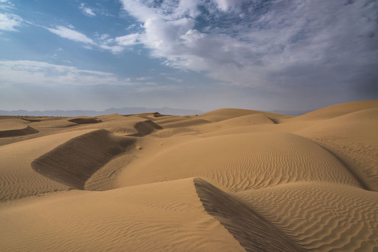 Sand dunes in desert against sky
