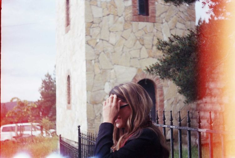 Portrait of young woman looking at building