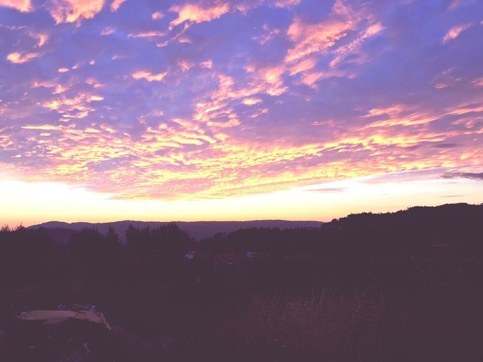 Silhouette landscape against dramatic sky during sunset