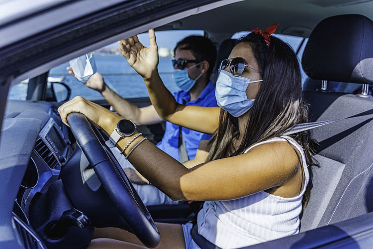 Couple with facemask arguing while she is driving a car in a dangerous