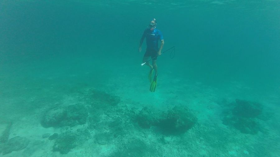 Full length of man spearfishing while snorkeling in turquoise sea