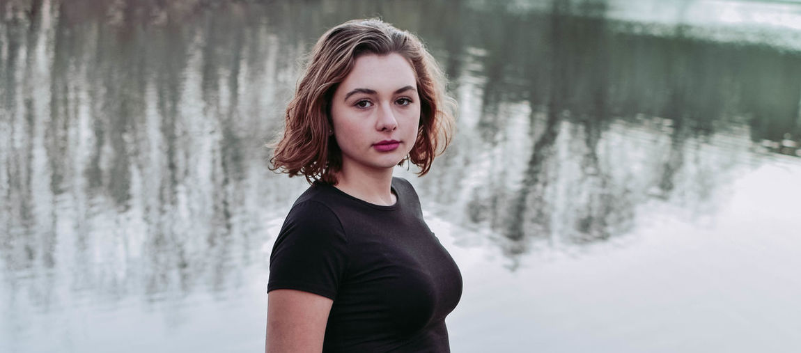 Portrait of beautiful woman standing against lake