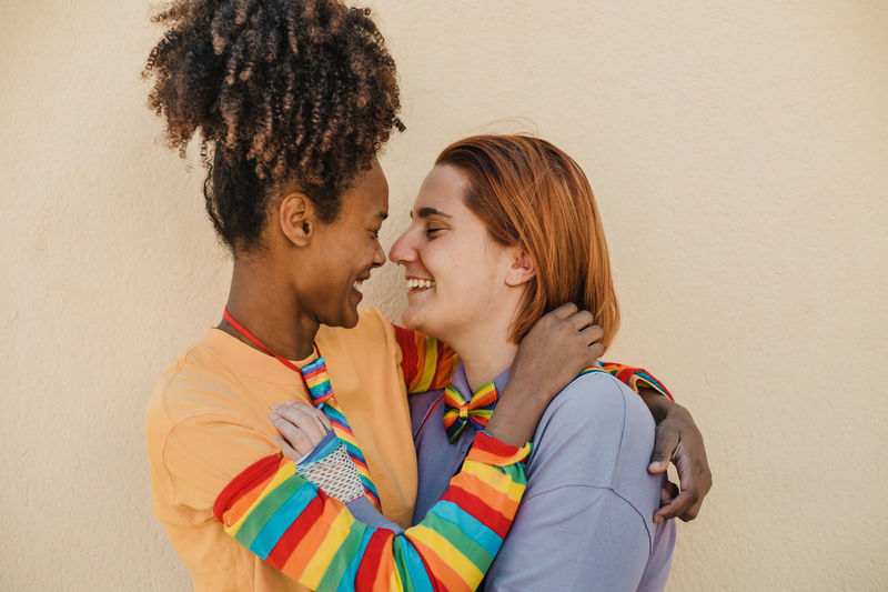 Lesbians smiling against wall