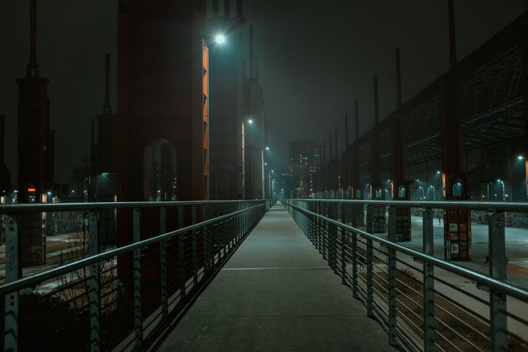 Rear view of woman walking on bridge at night