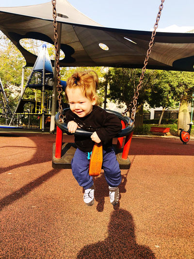 Cute boy playing on swing at playground