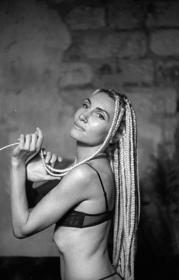 Side view of young woman with dreadlocks wearing bikini against wall