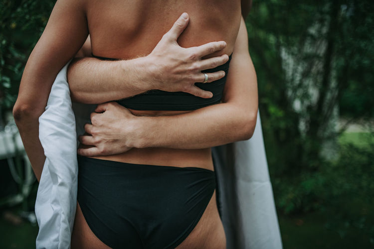 Midsection of couple embracing while standing outdoors
