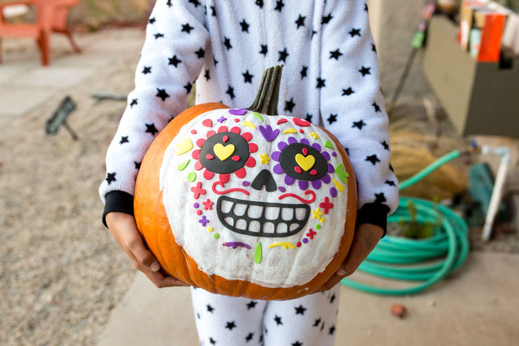 Dia de los muertos pumpkin designed and held by a child