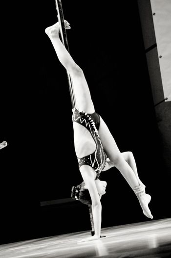 Full length of flexible dancer performing on pole
