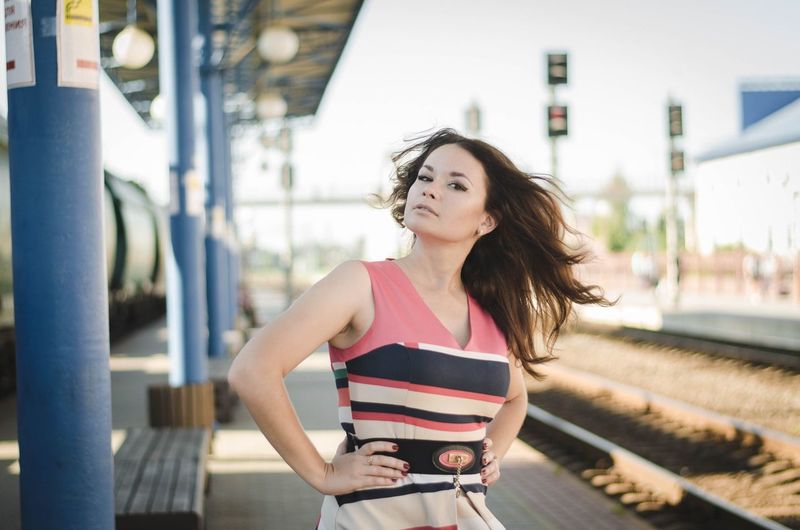 Portrait of confident woman standing on railroad station platform