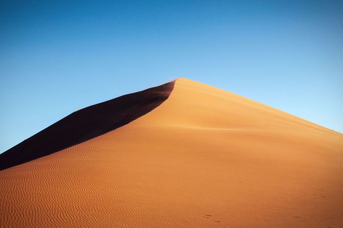 Low angle view of sand dune at namib desert against clear sky