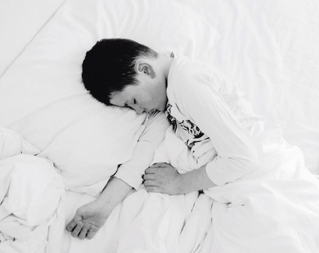 High angle view of boy sleeping on bed at home
