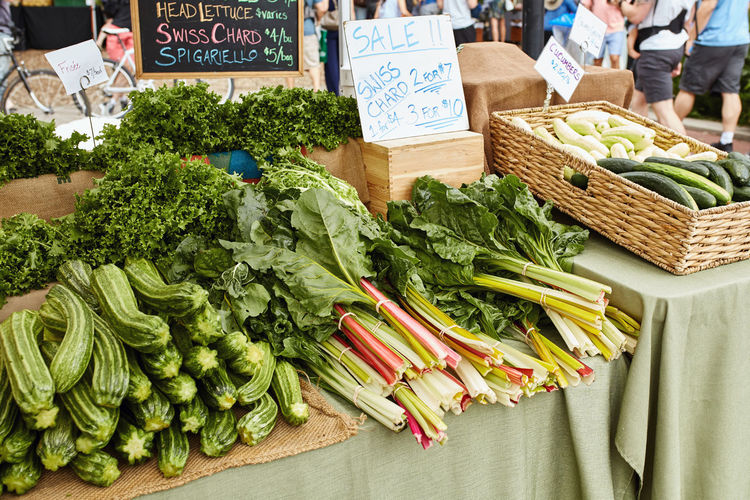 Display of zucchini, frisée and swiss chard for sale at a farmers market in boulder, colorado, usa