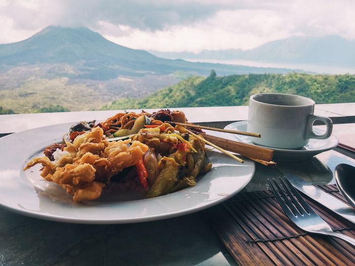 Close-up of food and coffee on table against mountain