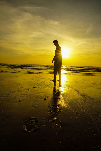 Full length of silhouette man standing on beach during sunset