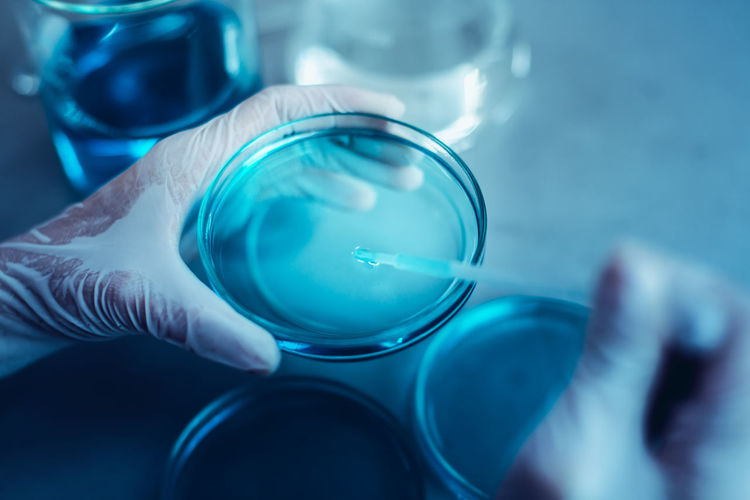 Cropped hands performing experiment on chemicals in laboratory