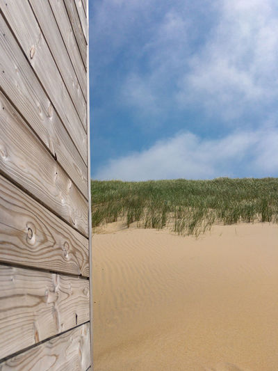 Summertime picture with gray patina wood in front of sand dunes and blue sky