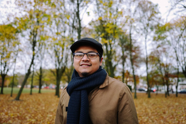 Portrait of smiling man wearing flat cap against trees at park during autumn