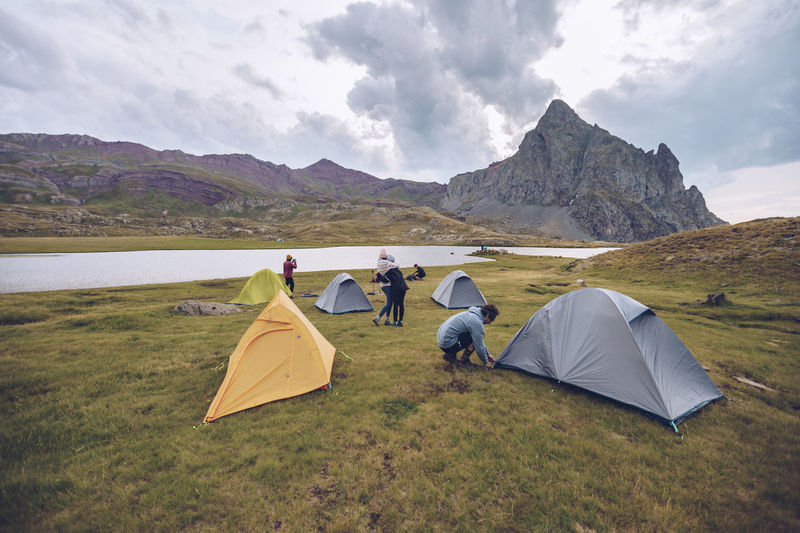 Friends preparing camp by lake at ibones of anayet