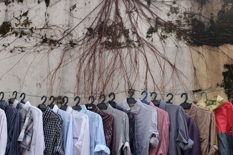 Shirts hanging on clothesline for sale against wall