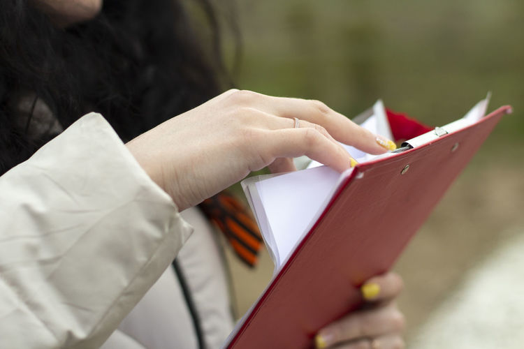 The secretary holds a tablet with papers. the girl is holding an office paper with text. 