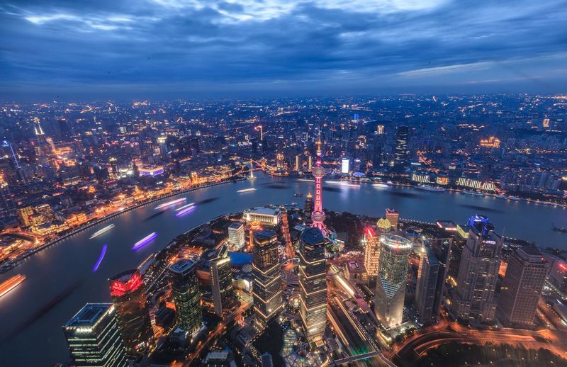 High angle view of oriental pearl tower and huangpu river in city at dusk
