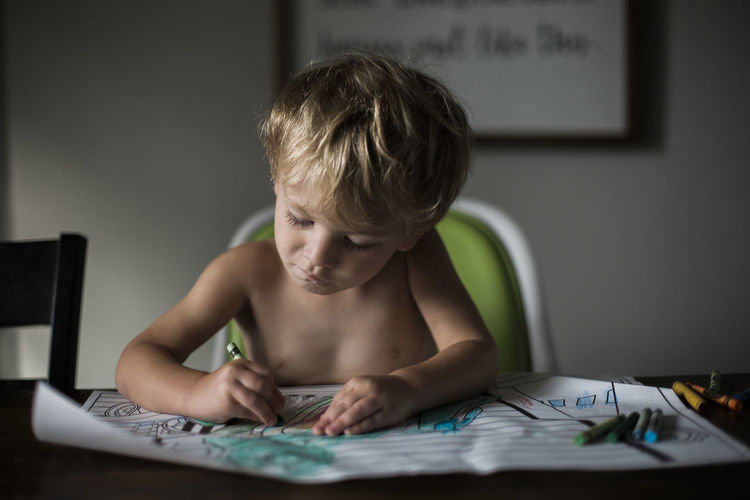 Young boy coloring at kitchen table