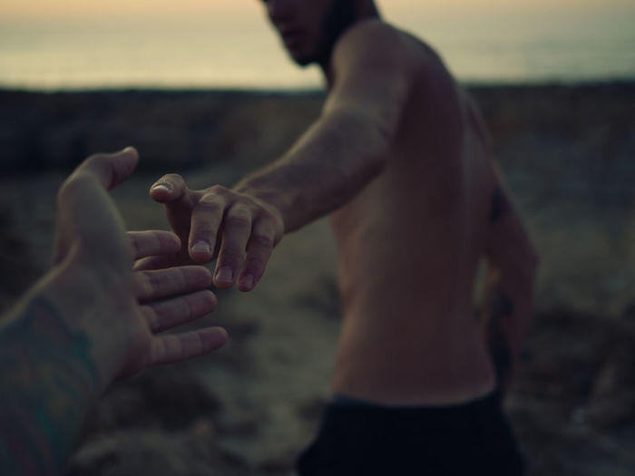 Cropped hand touching gay man at dusk