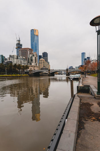 Buildings by river against sky in city, melbourne,