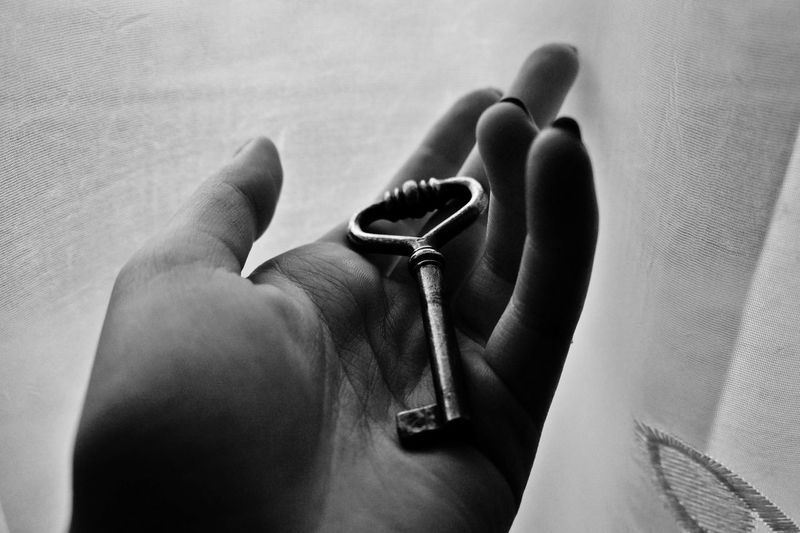 Cropped image of woman holding key against curtain