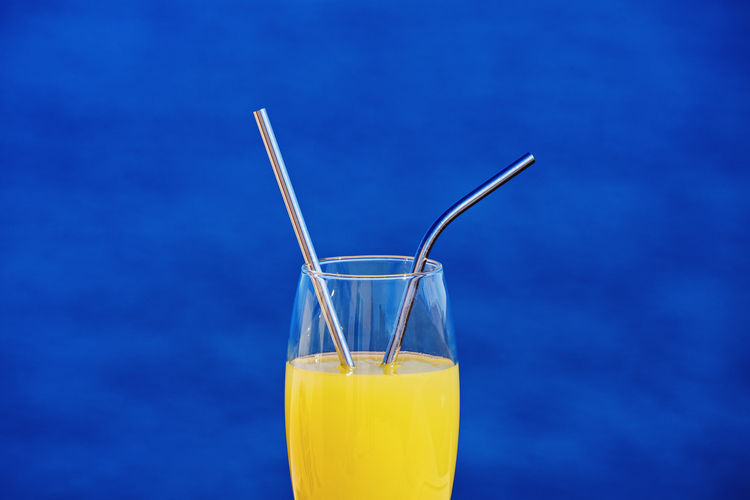 Close-up of juice in glass against blue wall
